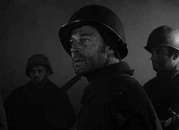 Movie still from “Battleground” (1949), directed by William A. Wellman – A black and white photo of a man wearing a helmet; Close Up shot, Low angle
