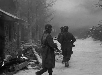 Movie still from “Battleground” (1949), directed by William A. Wellman – A black and white photo of a group of soldiers walking down a road; Medium shot, Low angle