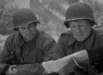 Movie still from “Battleground” (1949), directed by William A. Wellman – Two men wearing helmets are looking at a newspaper; Close Up shot, Low angle