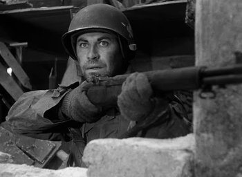 Movie still from “Battleground” (1949), directed by William A. Wellman – A man wearing a helmet and holding a rifle; Close Up shot, Low angle