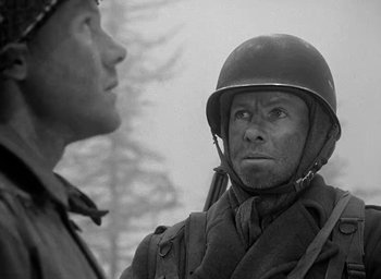 Movie still from “Battleground” (1949), directed by William A. Wellman – A man in a helmet is talking to another man; Close Up shot, Over the shoulder angle