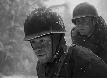 Movie still from “Battleground” (1949), directed by William A. Wellman – A man in a helmet is standing next to another man in a helmet; Close Up shot, Low angle