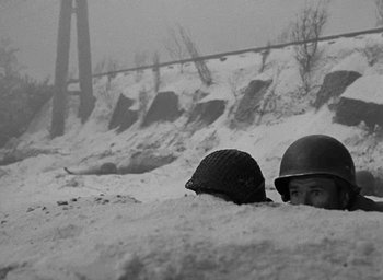 Movie still from “Battleground” (1949), directed by William A. Wellman – Two men in helmets are hiding in the snow; Medium shot, High angle