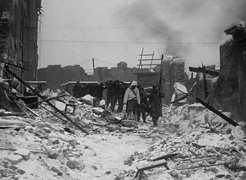 Movie still from “Battleground” (1949), directed by William A. Wellman – A black and white photo of a group of people standing in the rubble; Wide shot, Low angle