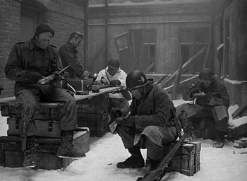 Movie still from “Battleground” (1949), directed by William A. Wellman – A group of men sitting on top of a wooden bench; Wide shot, High angle