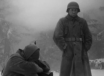 Movie still from “Battleground” (1949), directed by William A. Wellman – A man in a military uniform standing next to another man in a military uniform; Medium shot, Over the shoulder angle
