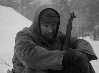 Movie still from “Battleground” (1949), directed by William A. Wellman – A man holding a gun in a black and white photo; Medium shot, Low angle