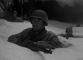 Movie still from “Battleground” (1949), directed by William A. Wellman – A group of soldiers in the snow with a gun; Medium shot, Low angle
