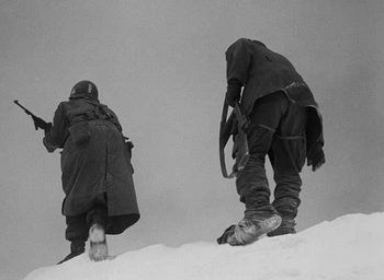Movie still from “Battleground” (1949), directed by William A. Wellman – Two men in winter gear standing on a snowy hill; Medium shot, Low angle
