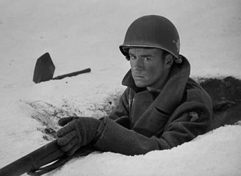 Movie still from “Battleground” (1949), directed by William A. Wellman – A man wearing a helmet and holding a rifle; Medium shot, High angle