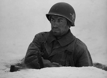 Movie still from “Battleground” (1949), directed by William A. Wellman – A man wearing a helmet is sitting in the snow; Medium shot, High angle