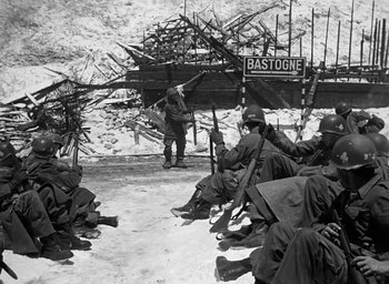 Movie still from “Battleground” (1949), directed by William A. Wellman – A black and white photo of a group of men sitting in the snow; Wide shot, High angle