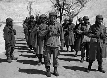 Movie still from “Battleground” (1949), directed by William A. Wellman – A group of men in military uniforms standing on a dirt road; Wide shot, Low angle
