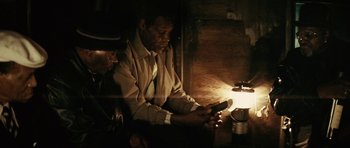 Movie still from “Be Kind Rewind” (2008), directed by Michel Gondry – A man sitting in front of a cell phone in a dimly - lit room; Close Up shot, High angle
