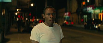 Movie still from “Be Kind Rewind” (2008), directed by Michel Gondry – A man in a white t - shirt standing on the street; Close Up shot, Over the shoulder angle