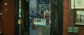 Movie still from “Be Kind Rewind” (2008), directed by Michel Gondry – A man holding up a closed sign behind a fence; Medium shot, High angle