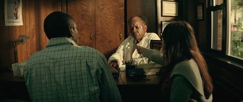 Movie still from “Be Kind Rewind” (2008), directed by Michel Gondry – A man sitting at a table talking to two other people; Medium shot, Over the shoulder angle