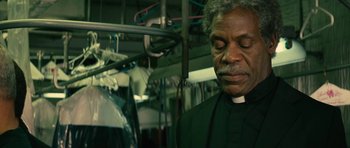 Movie still from “Be Kind Rewind” (2008), directed by Michel Gondry – A man wearing a priest's outfit in front of a row of clothes; Close Up shot, Low angle