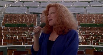 Movie still from “Beaches” (1988), directed by Garry Marshall – A woman with red curly hair is holding a microphone; Medium shot, High angle
