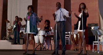 Movie still from “Beaches” (1988), directed by Garry Marshall – A couple of people that are singing on a stage; Medium shot, Low angle