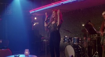 Movie still from “Beaches” (1988), directed by Garry Marshall – A woman with red hair singing into a microphone; Wide shot, Over the shoulder angle