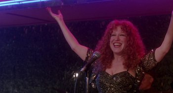 Movie still from “Beaches” (1988), directed by Garry Marshall – A woman with red curly hair is holding a microphone; Medium shot, Low angle