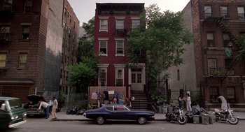 Movie still from “Beaches” (1988), directed by Garry Marshall – A car parked in front of a red brick building; Extreme Wide shot, High angle