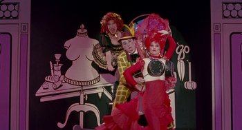Movie still from “Beaches” (1988), directed by Garry Marshall – A man and two women in costumes on a stage; Wide shot, High angle