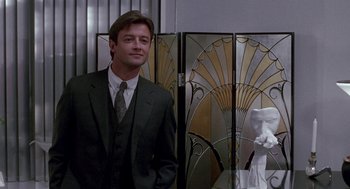 Movie still from “Beaches” (1988), directed by Garry Marshall – A man in a suit and tie standing in front of an art deco screen; Medium shot, Low angle