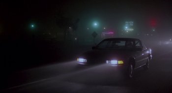 Movie still from “Beaches” (1988), directed by Garry Marshall – A car driving down a street at night with headlights on; Extreme Wide shot, Low angle