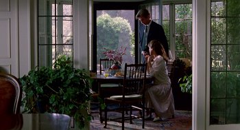 Movie still from “Beaches” (1988), directed by Garry Marshall – A man and a woman sitting at a dining room table; Wide shot, Low angle