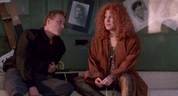 Movie still from “Beaches” (1988), directed by Garry Marshall – A man and a woman sitting next to each other on the floor; Medium shot, Over the shoulder angle