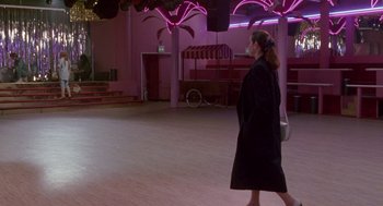 Movie still from “Beaches” (1988), directed by Garry Marshall – A woman in a black coat walking in a pink room; Wide shot, Over the shoulder angle