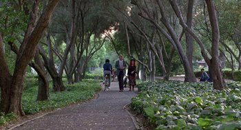 Movie still from “Beaches” (1988), directed by Garry Marshall – A group of people riding bikes down a path in a park; Extreme Wide shot, High angle