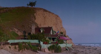 Movie still from “Beaches” (1988), directed by Garry Marshall – A house sitting on the side of a cliff by the ocean; Extreme Wide shot, Low angle