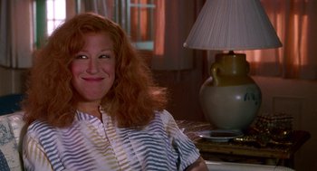 Movie still from “Beaches” (1988), directed by Garry Marshall – A woman sitting in front of a lamp in a room; Close Up shot, Over the shoulder angle