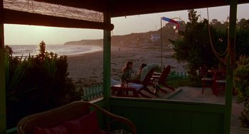 Movie still from “Beaches” (1988), directed by Garry Marshall – Two people sitting in lawn chairs on a porch overlooking the beach; Extreme Wide shot, High angle