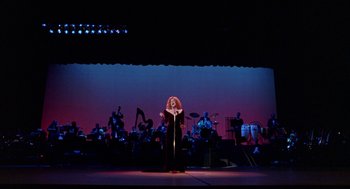Movie still from “Beaches” (1988), directed by Garry Marshall – A woman in a black dress is singing on a stage; Extreme Wide shot, Low angle