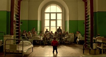 A group of people sitting in a room with a little boy standing in front of them