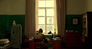 A woman sitting at a desk in front of a window