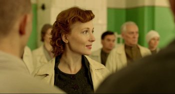 A woman with red curly hair is looking up