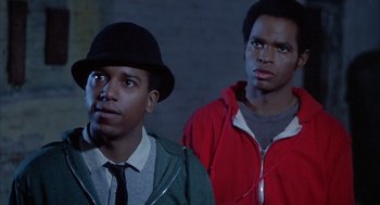 Movie still from “Beat Street” (1984), directed by Stan Lathan – Two young men standing next to each other in a dark room; Close Up shot, Low angle