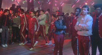 Movie still from “Beat Street” (1984), directed by Stan Lathan – A group of men in red and blue outfits dancing in front of a crowd; Wide shot, Low angle