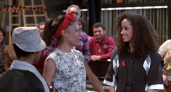Movie still from “Beat Street” (1984), directed by Stan Lathan – Two young women talking to each other in front of an audience; Medium shot, Over the shoulder angle