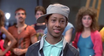 Movie still from “Beat Street” (1984), directed by Stan Lathan – A young man wearing a hat in front of a group of people; Close Up shot, Low angle