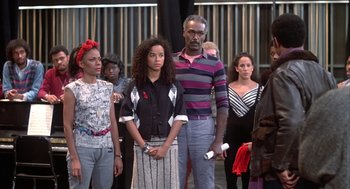 Movie still from “Beat Street” (1984), directed by Stan Lathan – A group of people standing around each other in front of a building; Medium shot, High angle