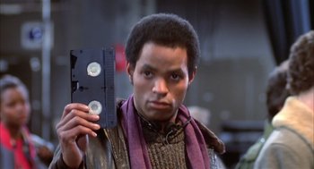 Movie still from “Beat Street” (1984), directed by Stan Lathan – A man holding a video tape in his hand; Close Up shot, Low angle