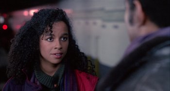 A young woman with curly black hair talking to a man