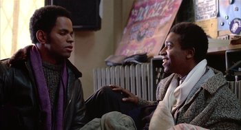 Movie still from “Beat Street” (1984), directed by Stan Lathan – Two young men are sitting on the floor talking; Medium shot, Over the shoulder angle