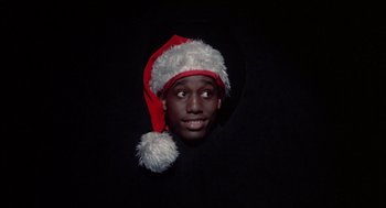 Movie still from “Beat Street” (1984), directed by Stan Lathan – A man wearing a santa clause hat and smiling for the camera; Close Up shot, Overhead angle